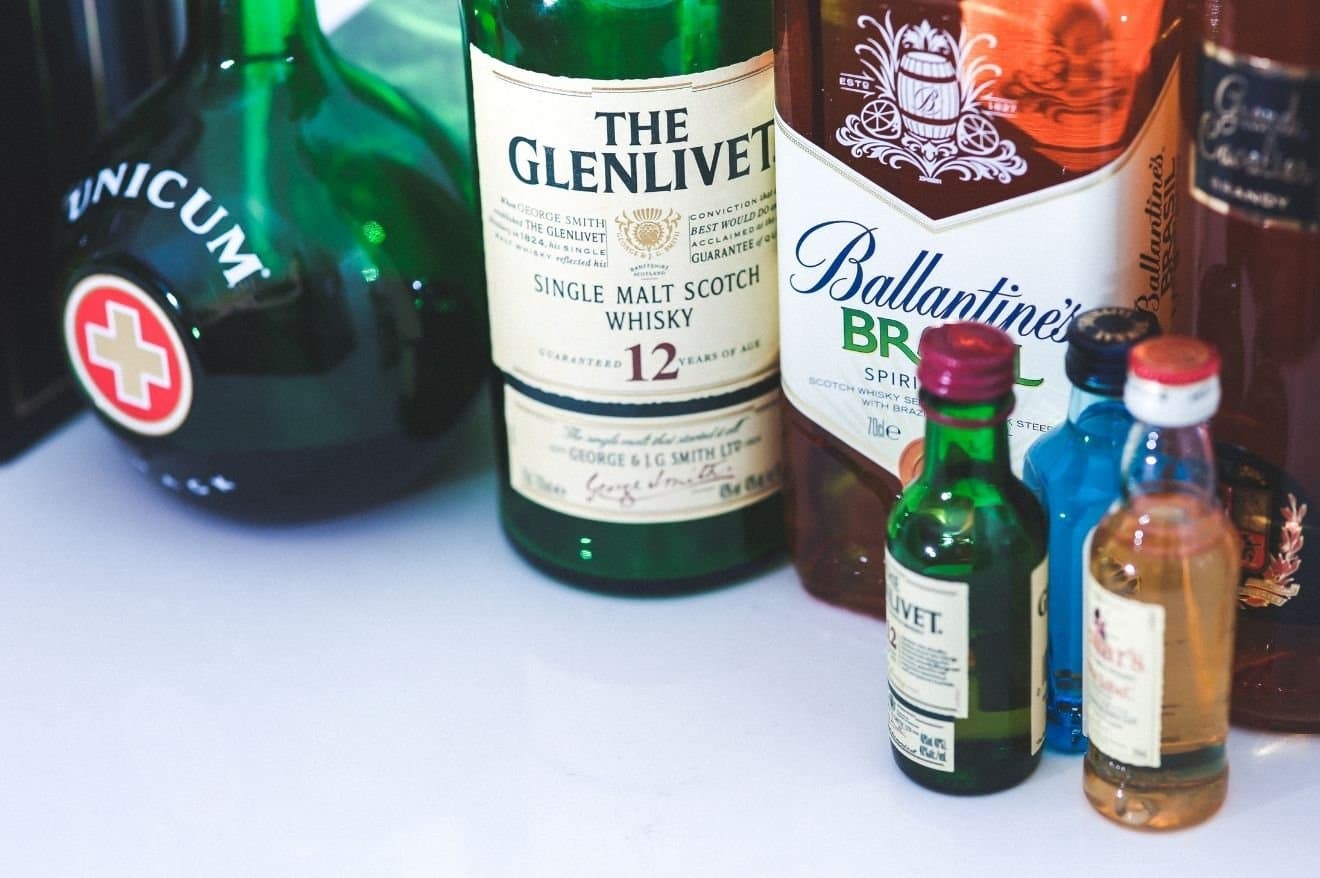 How to Tell if an Alcohol Bottle Has Been Opened and Resealed 1 A selection of liquor bottles displayed on a counter, showcasing various shapes and labels.