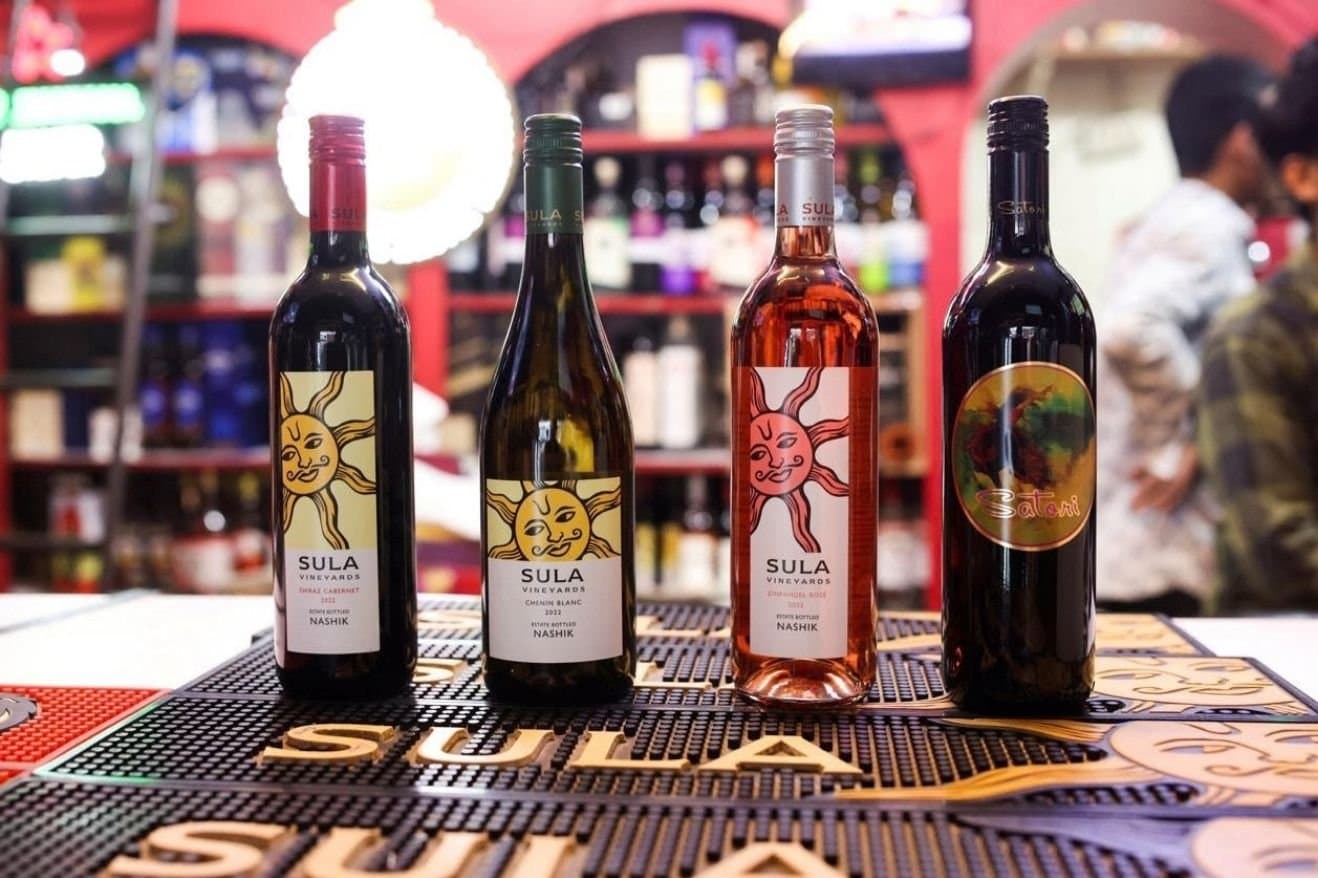 Sula Wines and Nashik: How the Region Became Associated with Indian Wine 30 A group of people enjoying a wine tasting event at Aluva Wine Bar, with glasses and bottles displayed on the table.